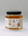 Jar of raw wildflower honey with a decorative label on a light gray background
